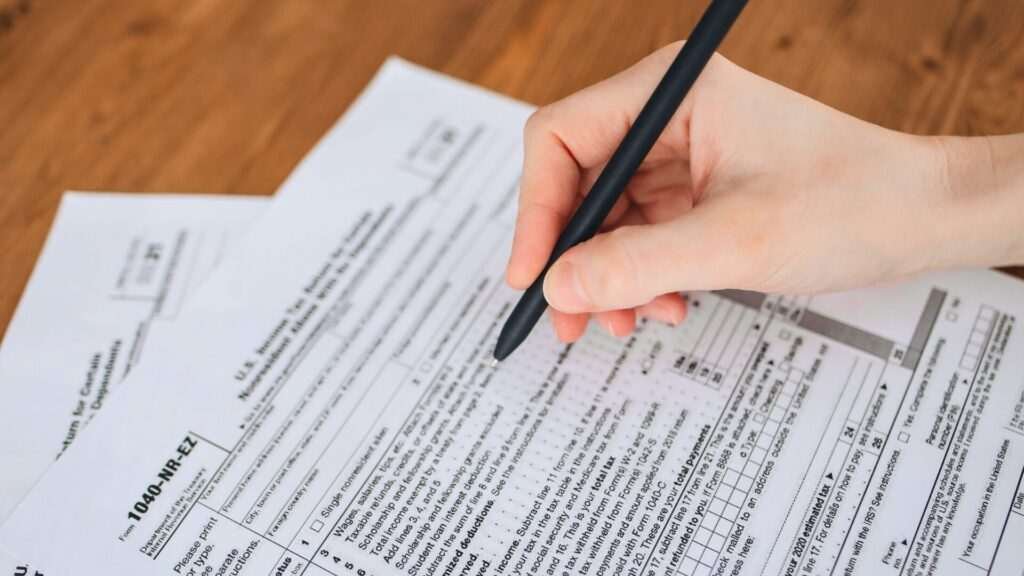 Hand completing tax forms on a table