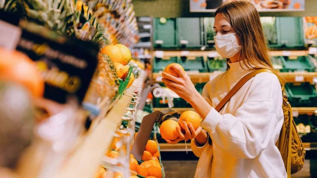 Woman shopping for fresh oranges in supermarket