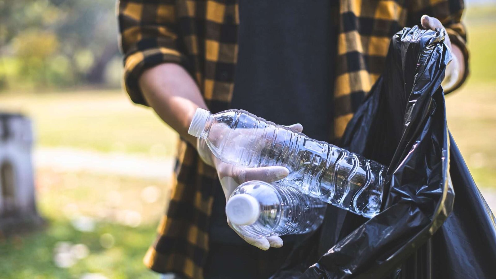 Person collecting plastic bottles in a park